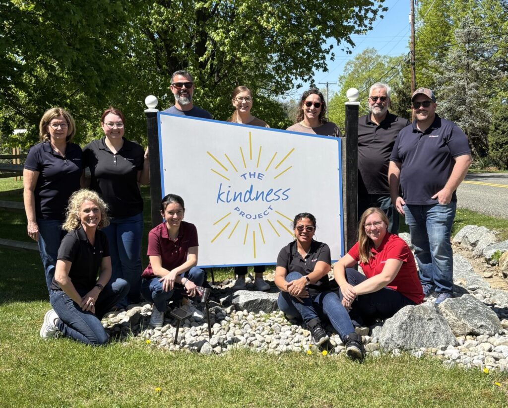Volunteers standing next to sign for The Kindness Project